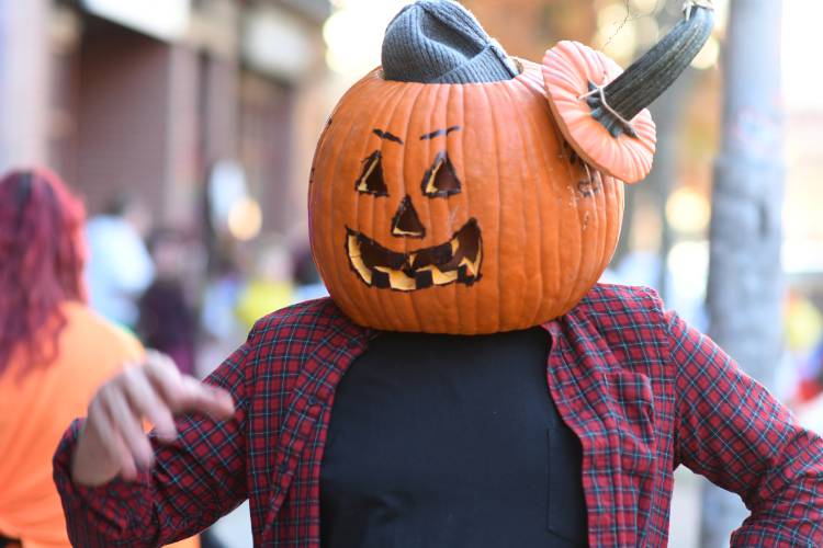 Pumpkin head with a real pumpkin trick-or-treating in Greenfield.