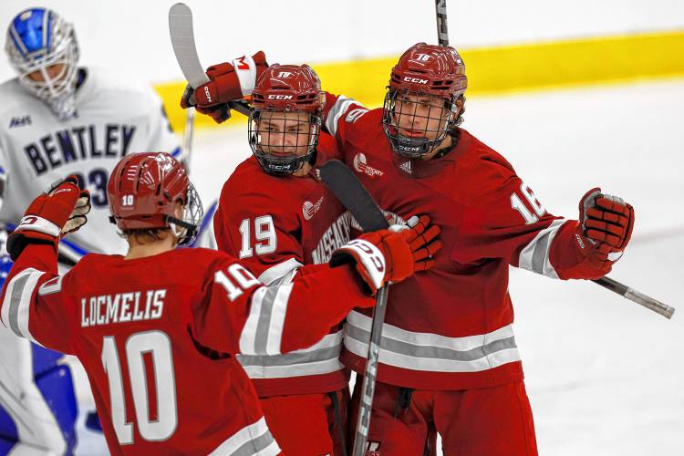 Massachusetts forward Aydar Suniev (16) celebrates with forward Cole O’Hara (19) and forward Dans Locmelis (10) after scoring a goal on Bentley goalie Connor Hasley (33) during the second period on Oct. 5 in Waltham.