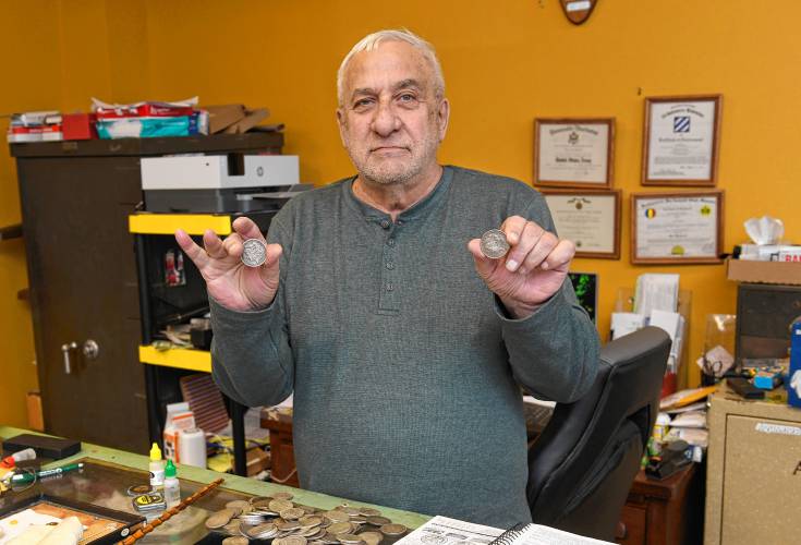 Gary Konvelski of Gary’s Coins and Antiques in Turners Falls holds up a real and a fake Morgan silver dollar. The fake is in his left hand.