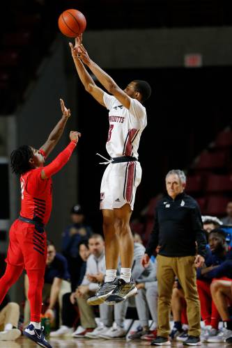 UMass guard Rahsool Diggins (3), right, takes a three-point shot over Duquesne defender Tevin Brewer (0) last season at the Mullins Center in Amherst.