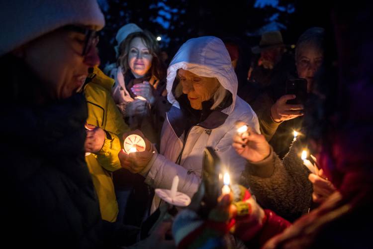 Rosalis Estes, center, keeps her candle lit in the drizzle at a vigil for grizzly bear No. 399 in Jackson, Wyo., Saturday Nov. 2, 2024.