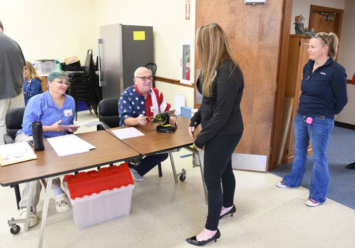 Orange poll workers Traci Beroldi and Ola Richard check in residents Jillian Bastine and Kristina Hartjens to vote at the Town Offices on Cheney Street on Tuesday.