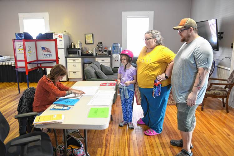 Montague poll worker Jenny Harrison checks in voters at the Gill-Montague Senior Center on Tuesday. Eleanor Larsen, 7, visited the polls with her parents Alice Glass and Adam Larsen.