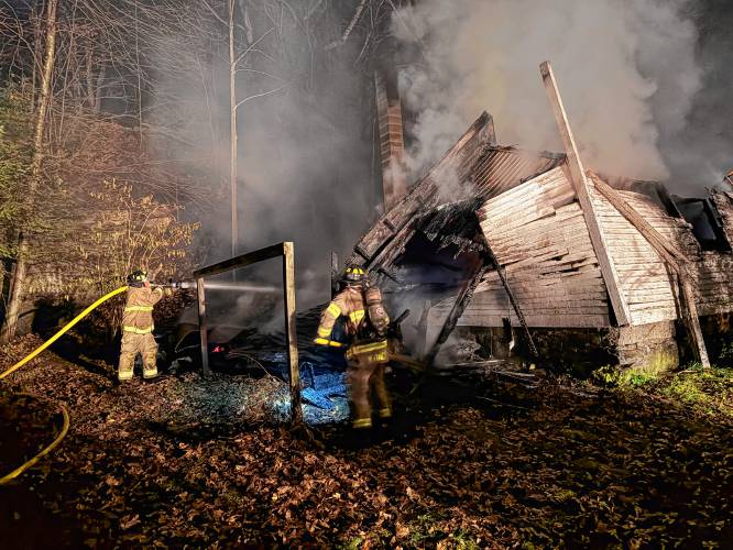 Firefighters from six departments work to knock down a Shelburne Falls shed fire that spread to the woods behind 18 South St., up to the railroad tracks, on Tuesday evening.