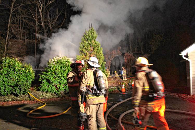 Firefighters from six departments work to knock down a Shelburne Falls shed fire that spread to the woods behind 18 South St., up to the railroad tracks, on Tuesday evening.