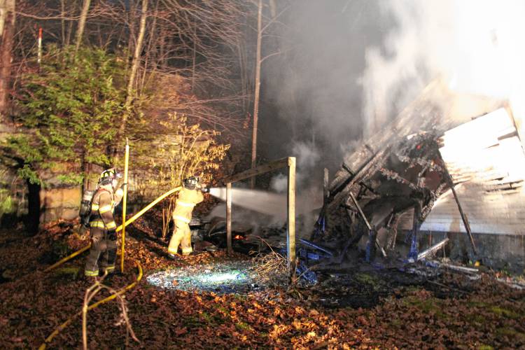 Firefighters from six departments work to knock down a Shelburne Falls shed fire that spread to the woods behind 18 South St., up to the railroad tracks, on Tuesday evening.