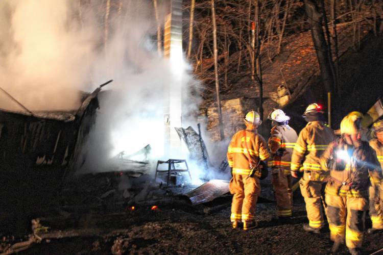 Firefighters from six departments work to knock down a Shelburne Falls shed fire that spread to the woods behind 18 South St., up to the railroad tracks, on Tuesday evening.