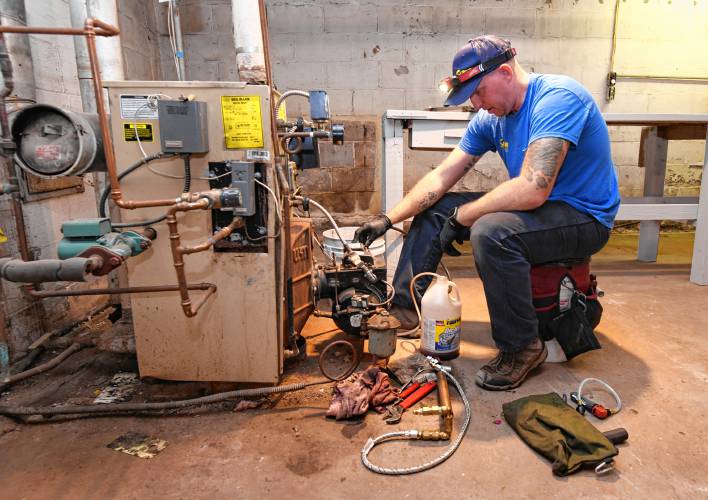 Andy Surner of Surner Heating works on an oil-burning furnace and water heater for a Montague resident.