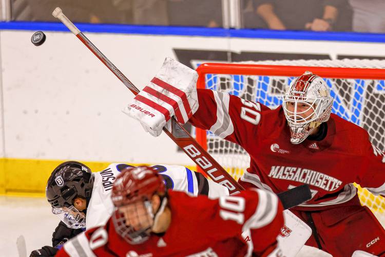 Massachusetts goalie Michael Hrabal (30) deflects a shot while Bentley forward Ryan Upson (38) and forward Dans Locmelis (10) duck out of the way during the second period of a game on Oct. 5 in Waltham.