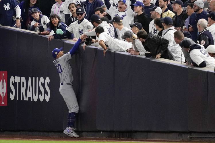 Fans interfere with a foul ball caught by Los Angeles Dodgers right fielder Mookie Betts during Game 4 of the World Series against the Yankees on Oct. 29.