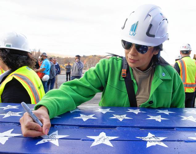 Liseth Velez, the founder and CEO of LJV Development, signs the steel beam along with many others during a “topping off” ceremony at the Veterans Home in Holyoke Thursday afternoon.