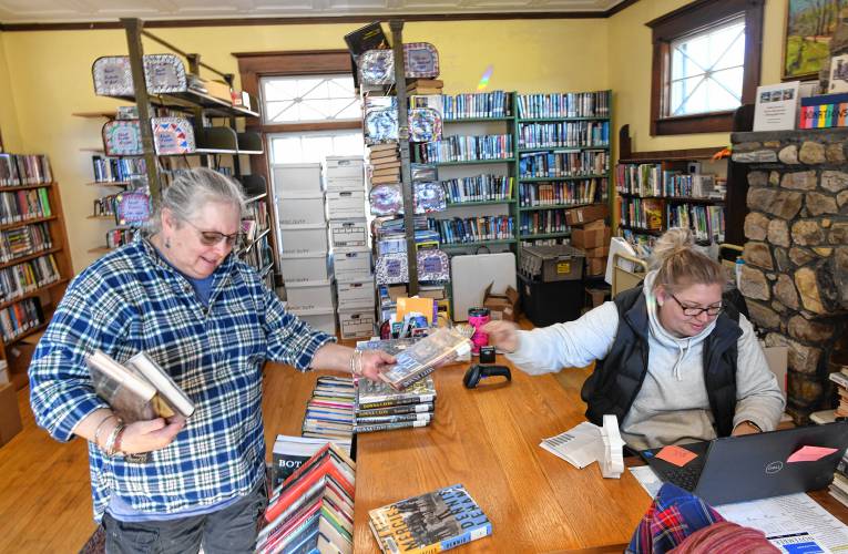 Volunteer Michele Higgins, left, helps Karin Parks, library director at Robertson Memorial Library in Leyden, assign barcodes to books in the collection so the library can participate in the Central and Western Massachusetts Automatic Resource Sharing (CWMARS) system.