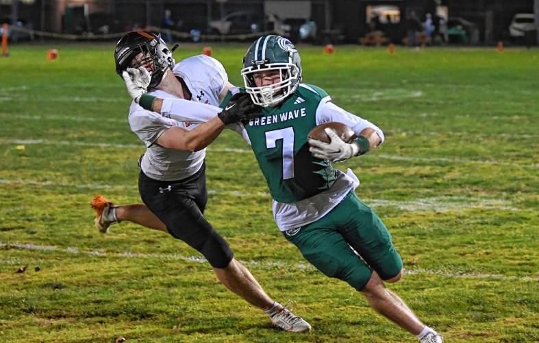 Greenfield’s Caleb Murray stiff-arms Belchertown’s Brian Fuller during the Green Wave’s 46-13 win at Veterans Memorial Field in Greenfield Friday night. 