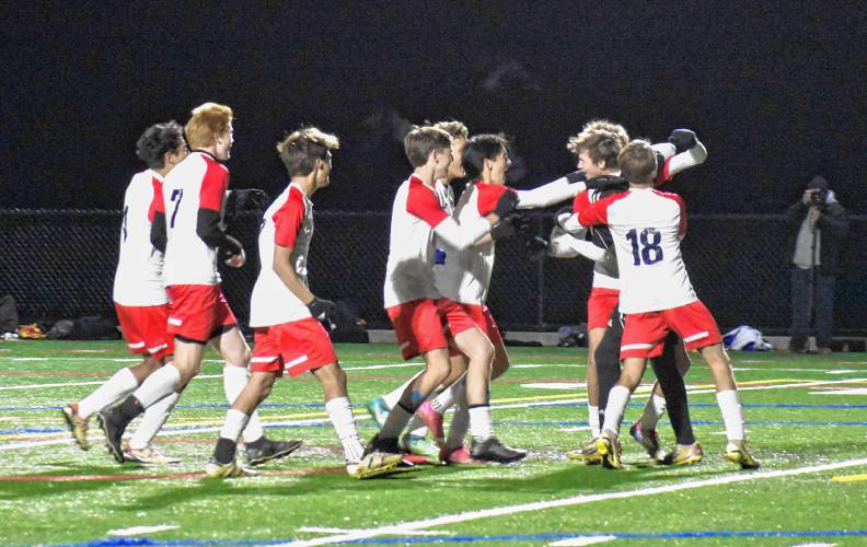 The Frontier boys soccer team swarms goalkeeper Jack Cusson after he stopped the final penalty kick in the Redhawks’ victory over Pittsfield in the MIAA Division 4 Round of 16 on Saturday at Berkshire Community College in Pittsfield.