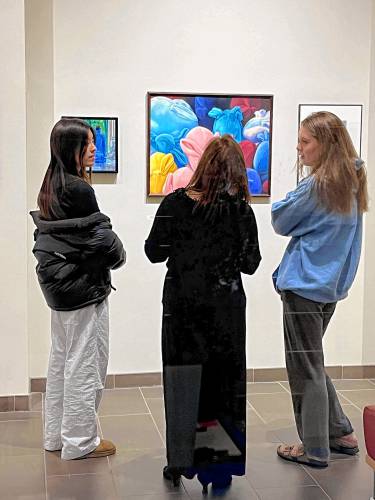 One of the artists with work on display at the Rhodes Arts Center gallery is Beth Roberge, a member of the Western Massachusetts Illustrators Guild who has been pursuing her passion of fine art since she was 7 years old. Roberge, center, talks with a pair of Northfield Mount Hermon School students during the gallery’s opening reception on Oct. 25.