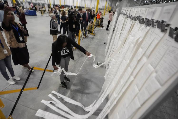 An elections staffer hangs scanner tapes used in early voting at the Fulton County Election Hub and Operation Center, Tuesday, Nov. 5, 2024, in Atlanta.