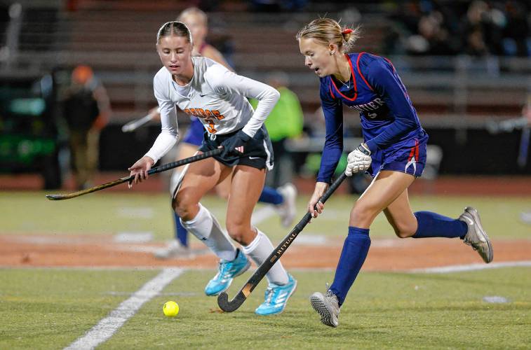 Frontier’s Ashlie Galenski (5) carries the ball upfield under pressure from Uxbridge’s Kendall Gilmore (3) in the first half of the MIAA Div. 4 field hockey state semifinal Tuesday at Agawam High School.