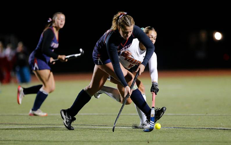 Frontier’s Harper Modestow (22) works to clear the ball under pressure from Uxbridge’s Amelia Blood (2) in the fourth quarter of the MIAA Div. 4 field hockey state semifinal Tuesday at Agawam High School.