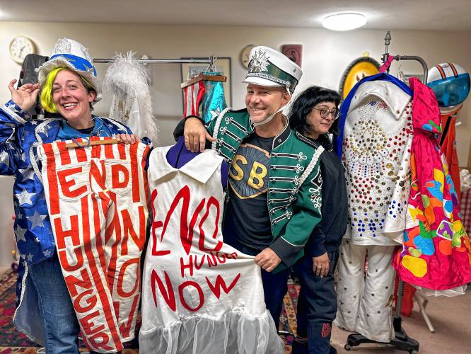 From left, Kathryn Greenwood Swanson (dressed as Uncle Sam), Christopher “Monte” Belmonte (dressed as a Greenfield Marching Band member) and Alex McGuigan (no costume) show off some of the costumes used during Belmonte’s annual march to support the Food Bank of Western Massachusetts.