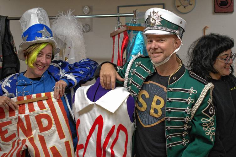 From left, Kathryn Greenwood Swanson (dressed as Uncle Sam), Christopher “Monte” Belmonte (dressed as a Greenfield Marching Band member) and Alex McGuigan (no costume) show off some of the costumes used during Belmonte’s annual march to support the Food Bank of Western Massachusetts.