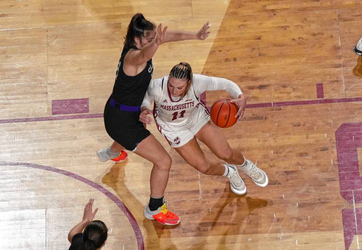 UMass’ Megan Olbrys (11) dribbles toward the basket while defended by a Holy Cross player during the Minutewomen’s 75-70 loss at the Mullins Center on Wednesday.