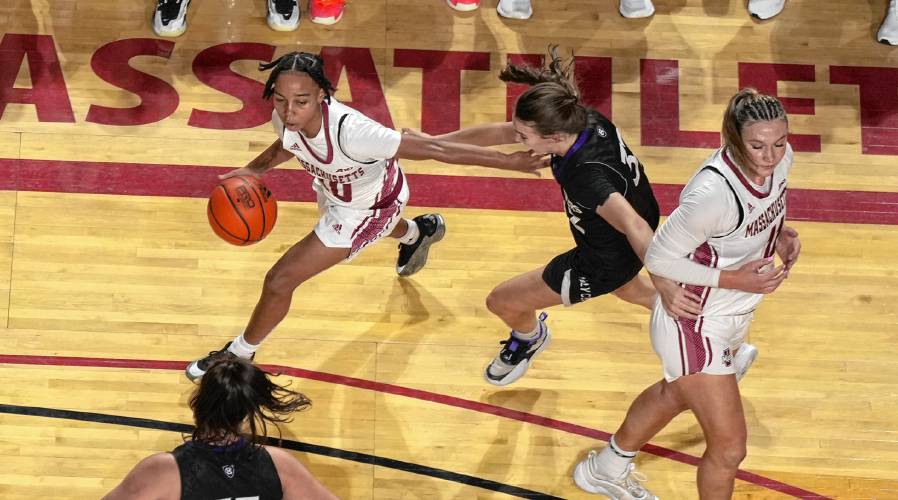 UMass’ Yahmani McKayle (10) dribbles around a Holy Cross player during the Minutewomen’s loss at the Mullins Center on Wednesday.