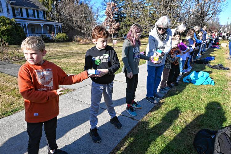 Third grade students Jeremiah Erho, Micah Christenson and Autumn Senser pass nonperishable items down the line as the school’s annual food drive concludes on Wednesday by transferring the collected items to the Northfield Food Pantry, located in the basement of Dickinson Memorial Library.