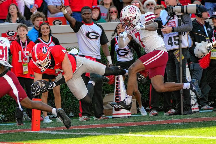 Georgia tight end Oscar Delp (4) dives in for a touchdown after a catch as UMass defensive back Lake Ellis (7) gives chase during the Minutemen’s 59-21 loss to the Bulldogs on Saturday afternoon at Sanford Stadium in Athens, Ga.