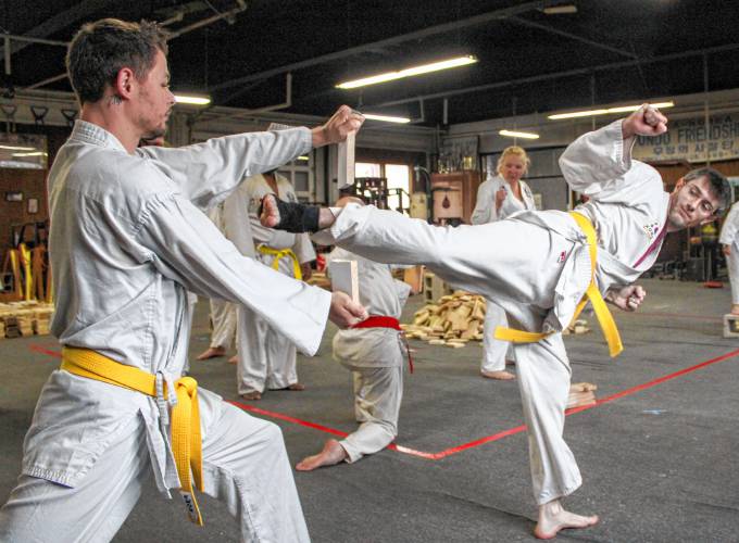 Greenfield resident Michael Grover holds a wooden board for Alan Fish as he breaks it with a swift roundhouse kick during the 22nd annual “Break-athon” at the Greenfield Tae Kwon Do Center.