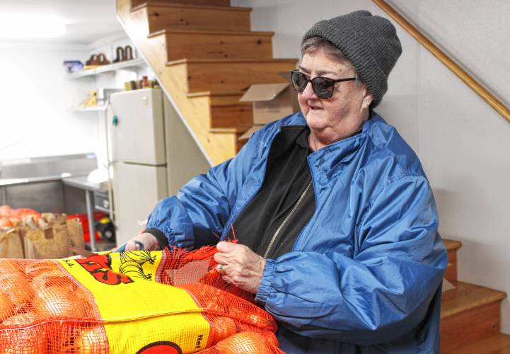 Charlene Czernich cuts open a big bag of onions while helping to assemble 150 Thanksgiving food boxes at the Schuetzen Verein in Gill on Monday morning.