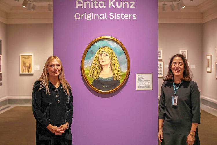 Anita Kunz, left, and “Original Sisters” curator Jane Dini pose alongside the illustrator’s bejeweled self-portrait. Tracing her forebears to 12th century Transylvania, she’s included a vampire bite on her neck.