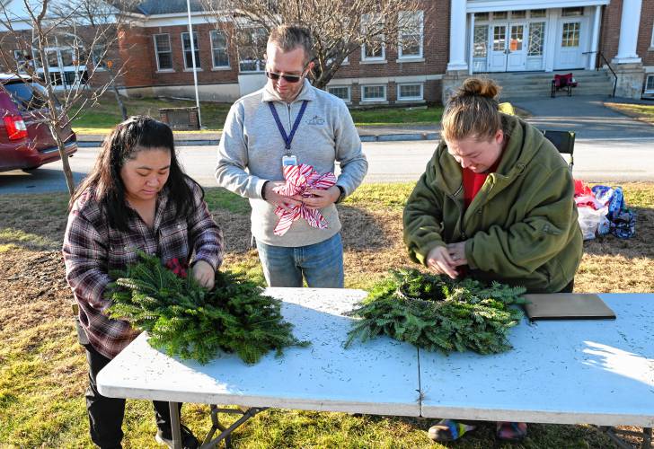 Kara Brown, Gary Conaway and Megan Beaulieu of the Northfield Elementary School Parent-Teacher  Organization (PTO) attach ribbons to the few remaining holiday wreaths that were sold as part of a fundraiser on Wednesday in Northfield.