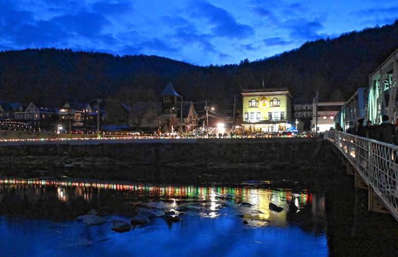 Holiday lights reflect in the Deerfield River at Moonlight Magic in Shelburne Falls on Friday night.