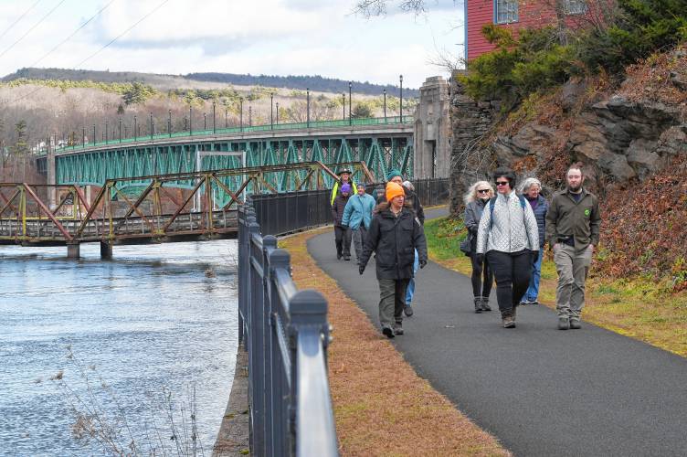 Janel Nockleby, visitor service supervisor at the Great Falls Discovery Center, left, leads a “Go Green on Black Friday” hike along the canalside bike path in Turners Falls on Friday.