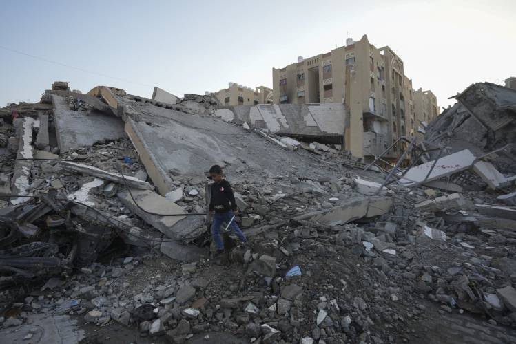 A Palestinian boy walks amongst rubble of destroyed buildings at a neighbourhood in Khan Younis, Gaza Strip, Sunday, Dec. 1, 2024.