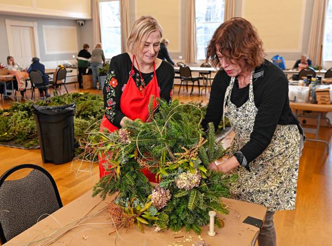 Greenfield resident Brenda Hannon and Gail Doering of Saratoga Springs, New York, former college roommates, team up to make a wreath during the Historic Deerfield wreath-making workshop on Tuesday.