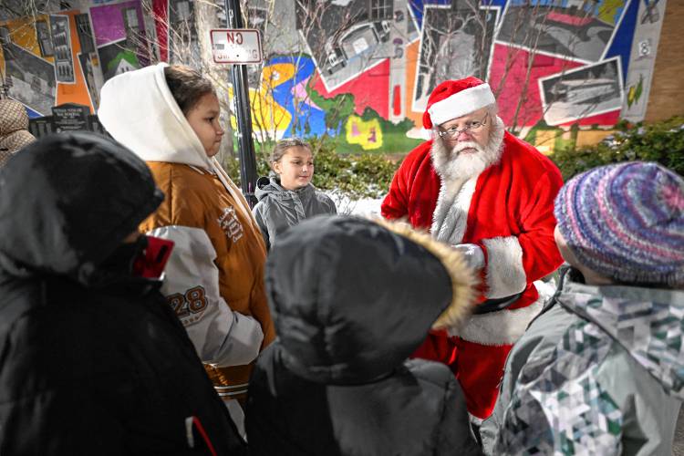 Santa talks with children giving out candy canes at Veterans Mall during the first night of Jingle Fest in Greenfield on Friday night.